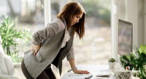 5 ασκήσεις για να αποφύγεις τον πόνο στην πλάτη στο γραφείο . Η εικόνα δείχνει ένα άτομο με πόνο στη μέση (freepik.com)